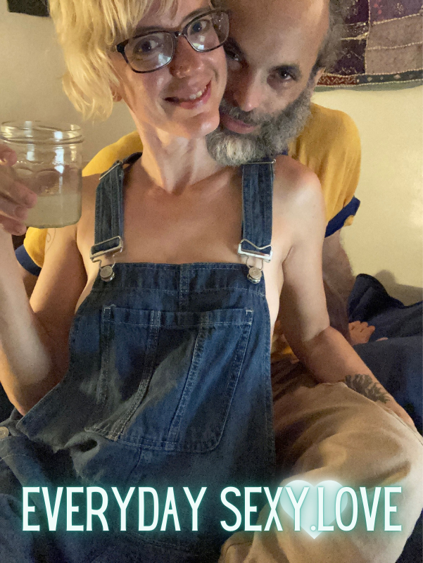 EverydaySexy.love cam models Reed Oshen has his arms and legs around his wife, Pearl as she poses in glasses and overalls with a smile on her face.